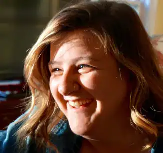 Smiling person in sunlight, indoors.