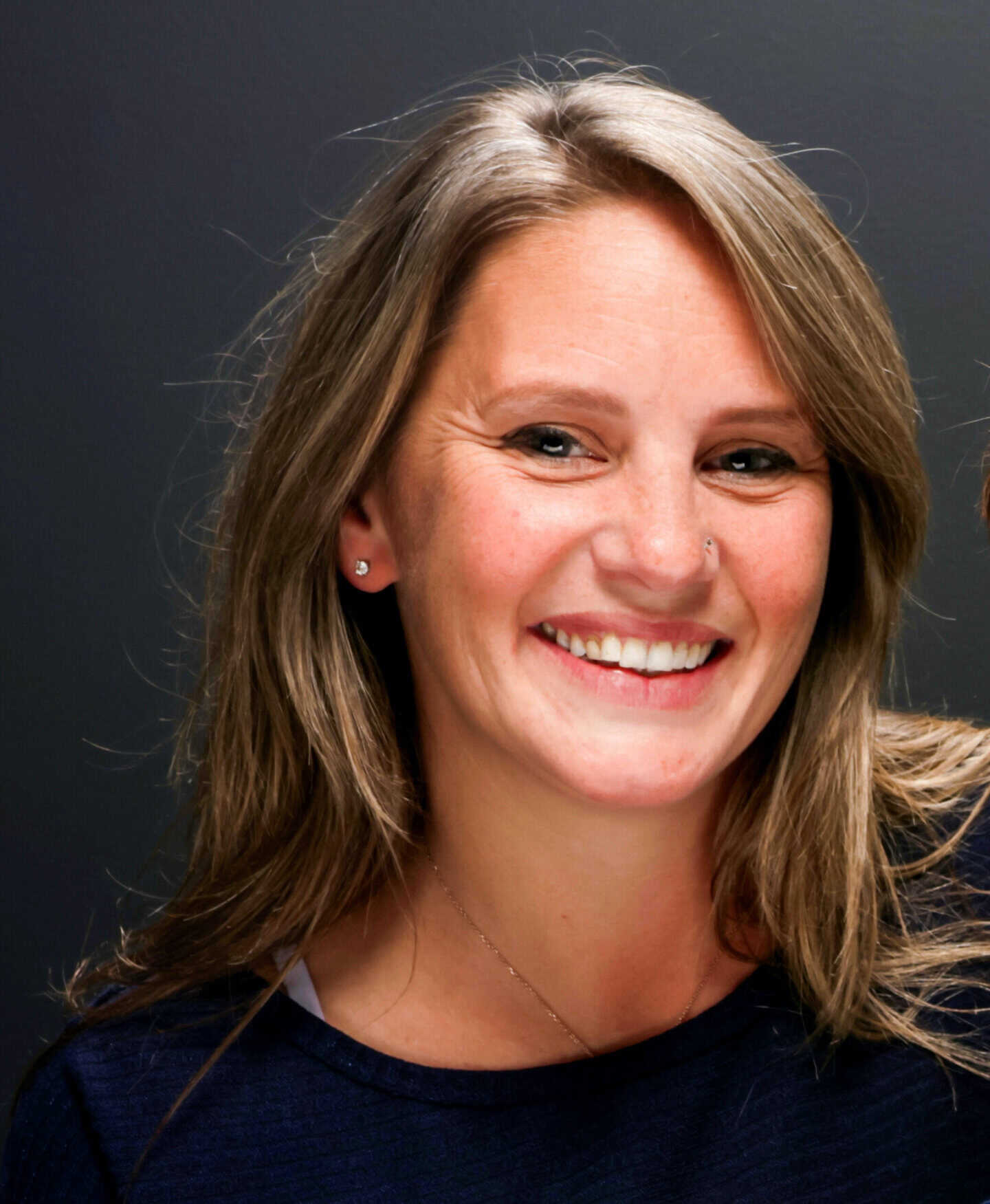 Woman smiling with long hair and earrings.