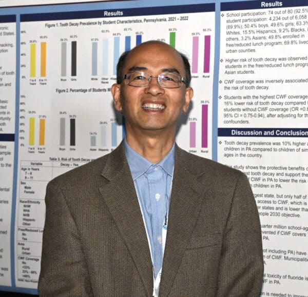 Man standing before tooth decay research poster