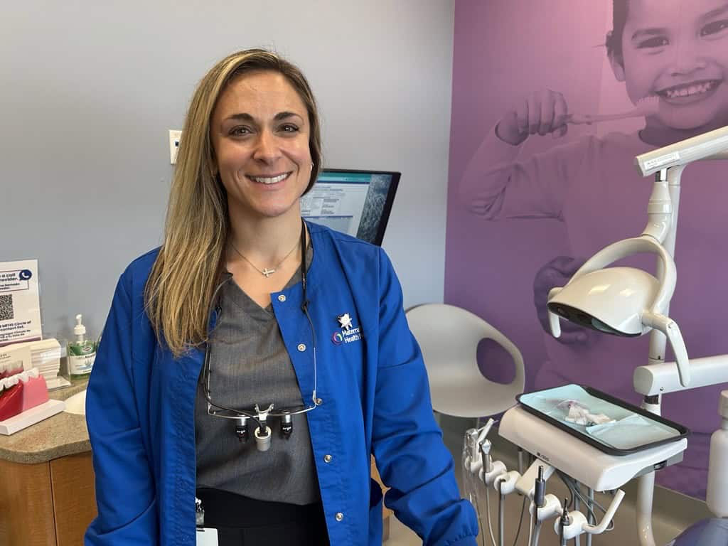 Smiling dental professional beside chair in pediatric clinic